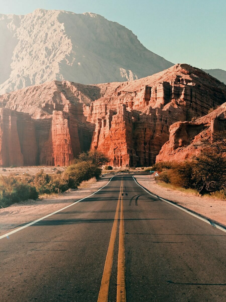 gray asphalt road near brown mountain during daytime